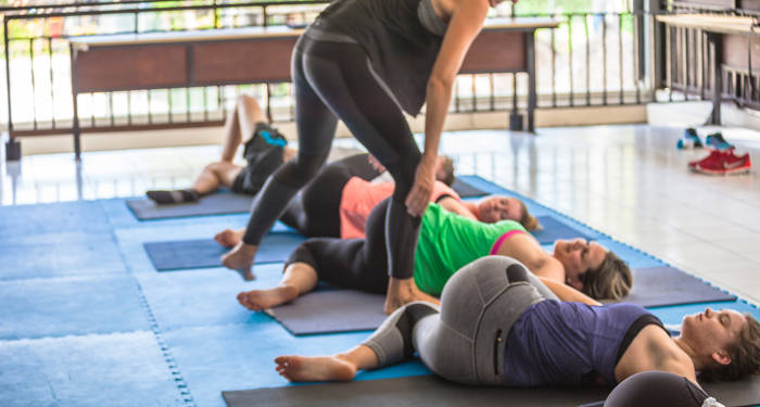 Kvinne hjelper yoga studenter med stillingene sine