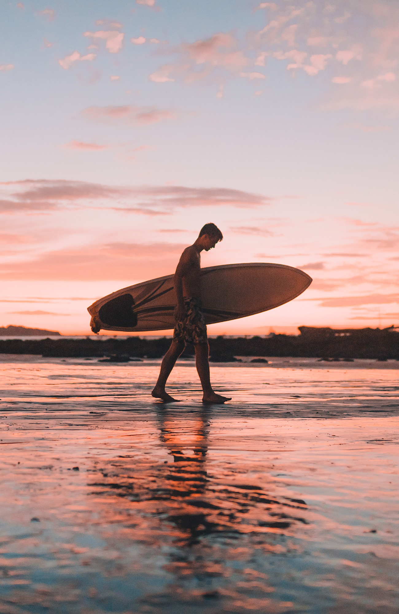 Mann som bærer surfebrettet sitt på en strand i Costa Rica. Foto.