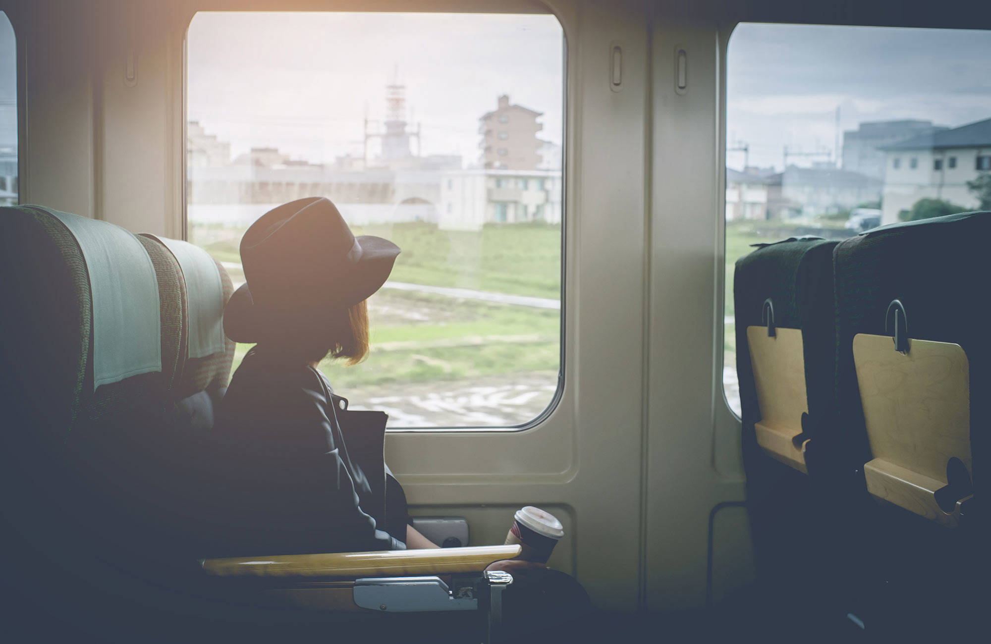 tjeuj med hatt tittar ut genom fönster i ett tåg