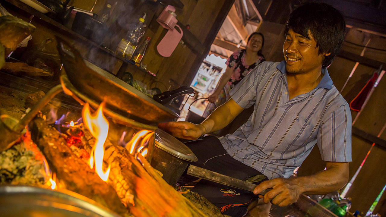 mann i thailand lager mat over åpen flamme