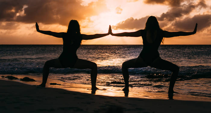 To kvinner praktiserer yoga på stranden på Bali