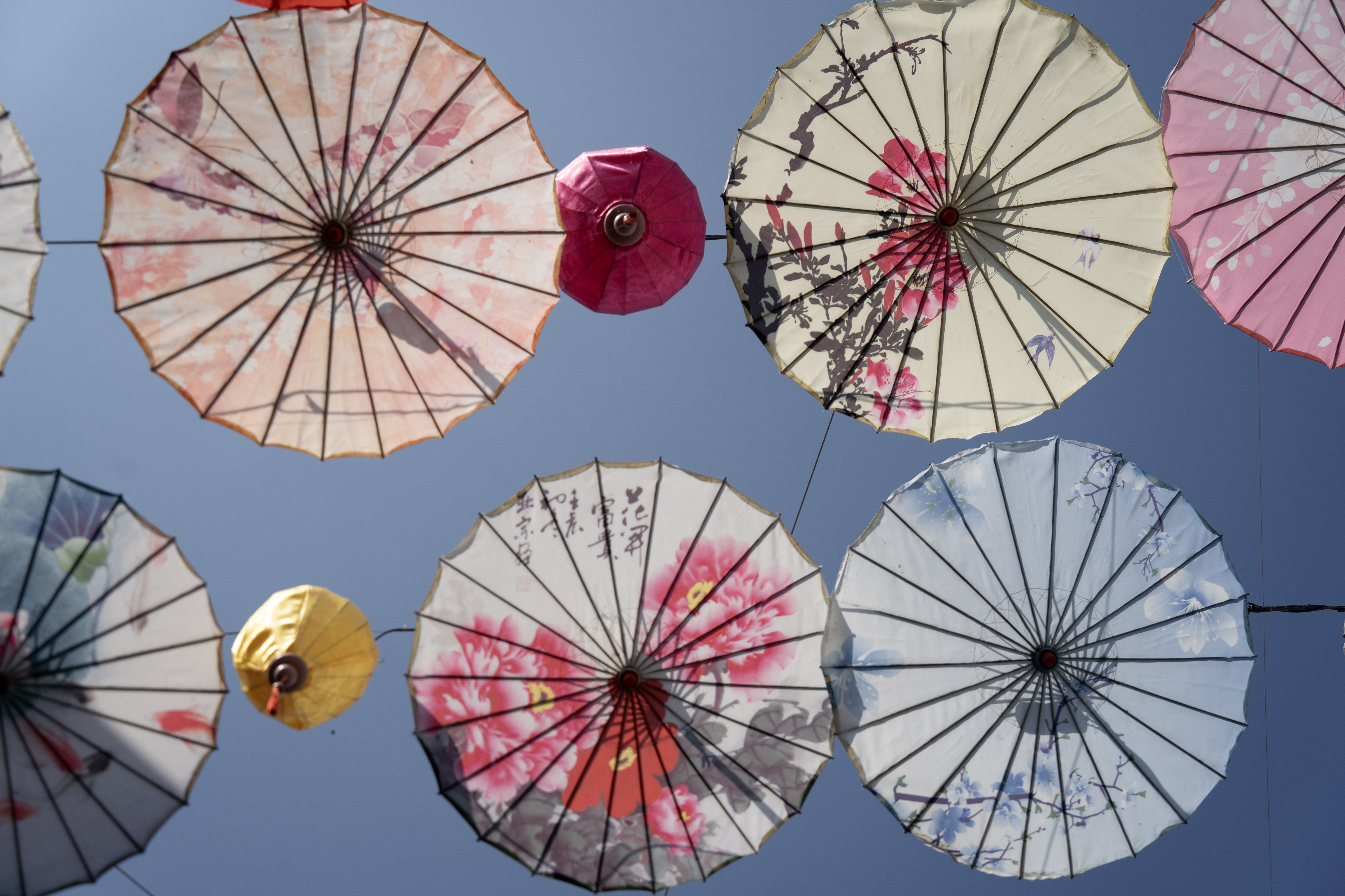 Paraplyer med motiv mot en blå himmel i Kina. Foto.