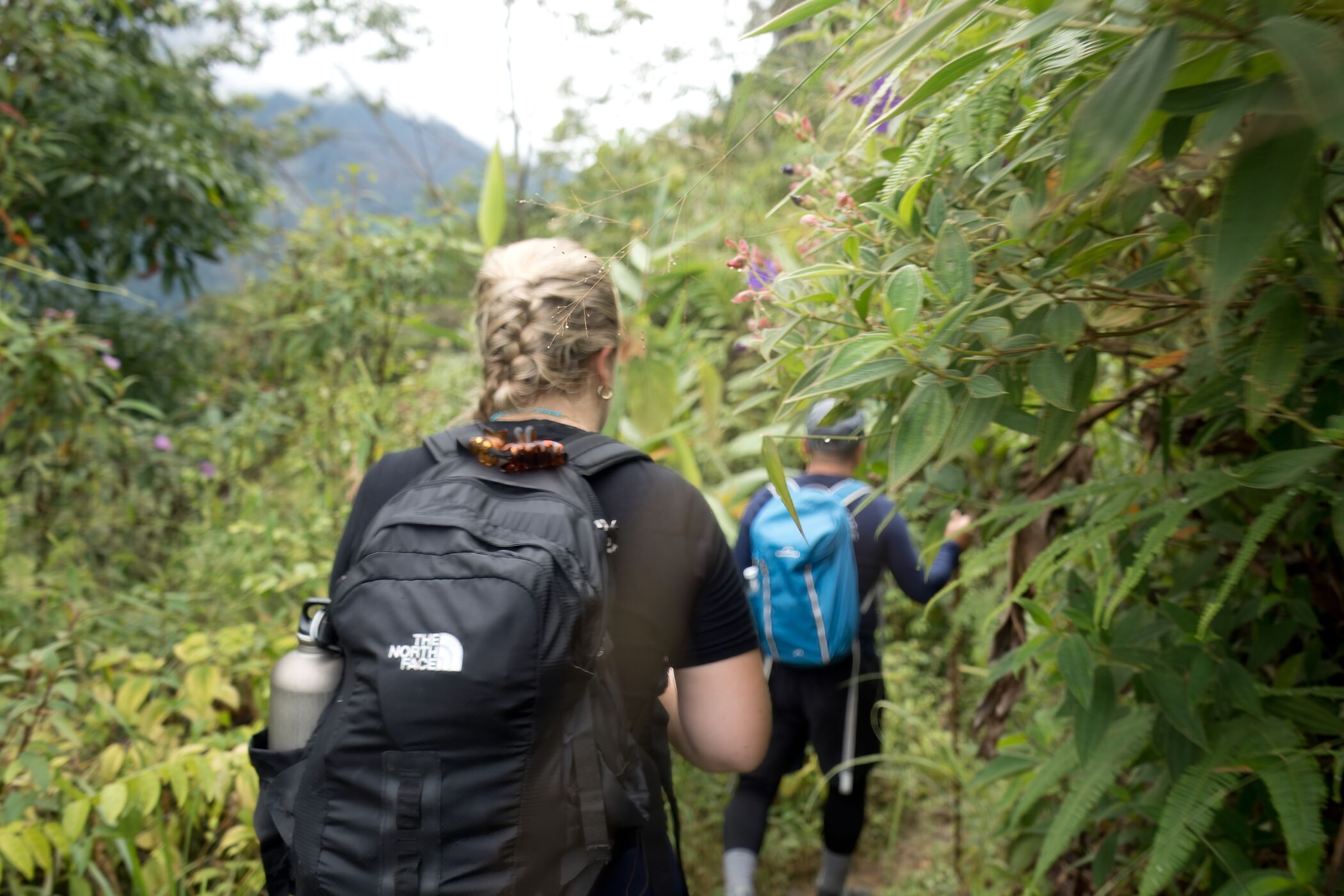 Group of girls in colourful clothes and with paint on their faces standing next to a lake in Pokhara, Nepal, with mountains in the background