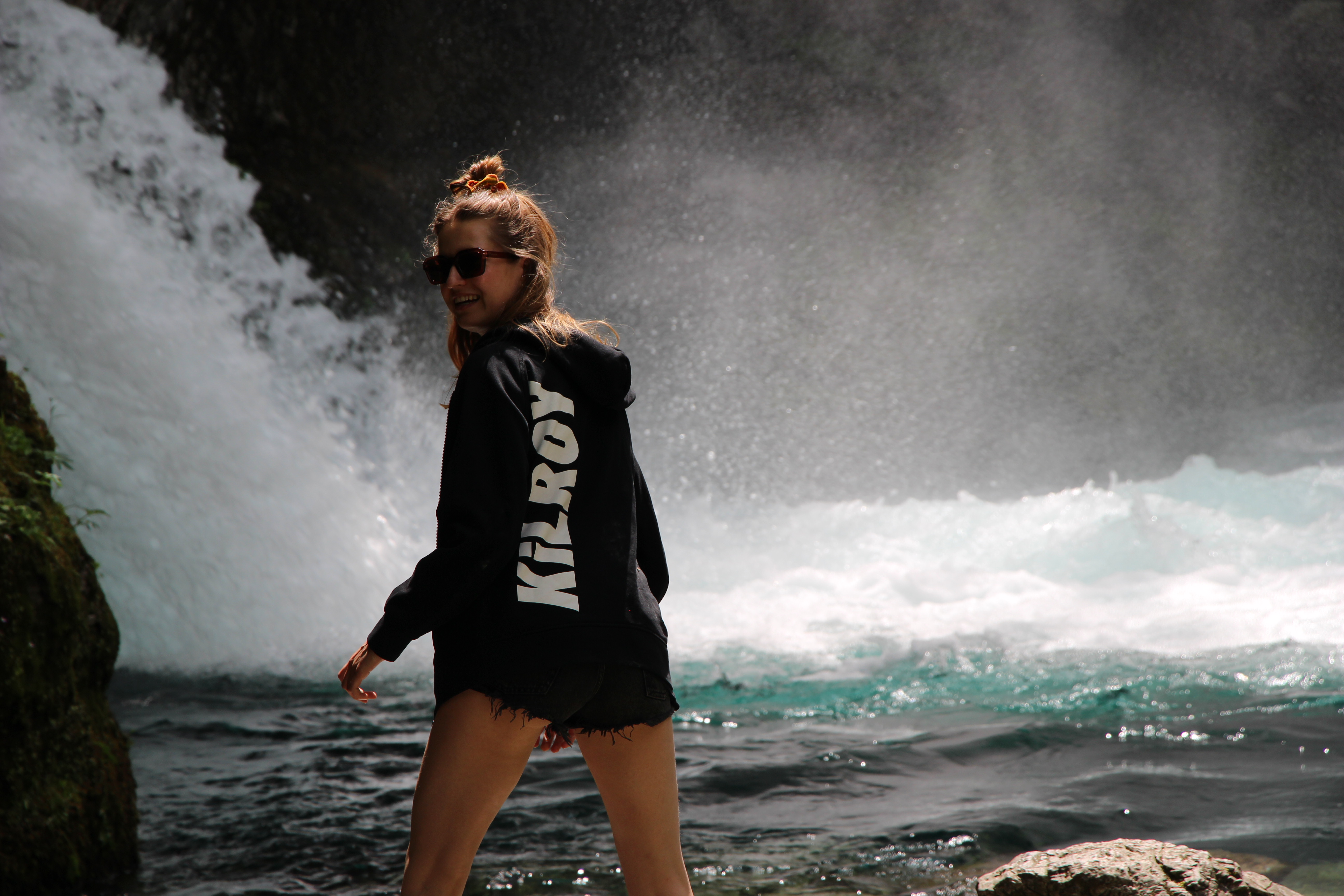 Girl with KILROY sweater next to waterfall