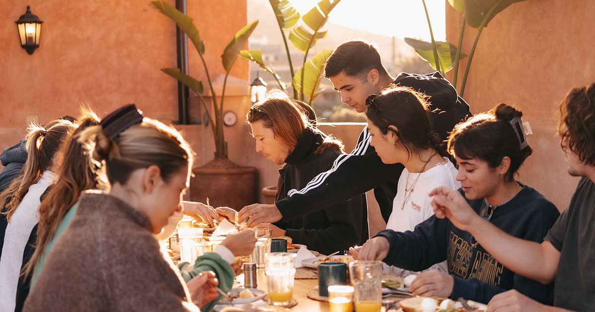 Folk rundt et bord på en surfcamp i Tamraght. Foto