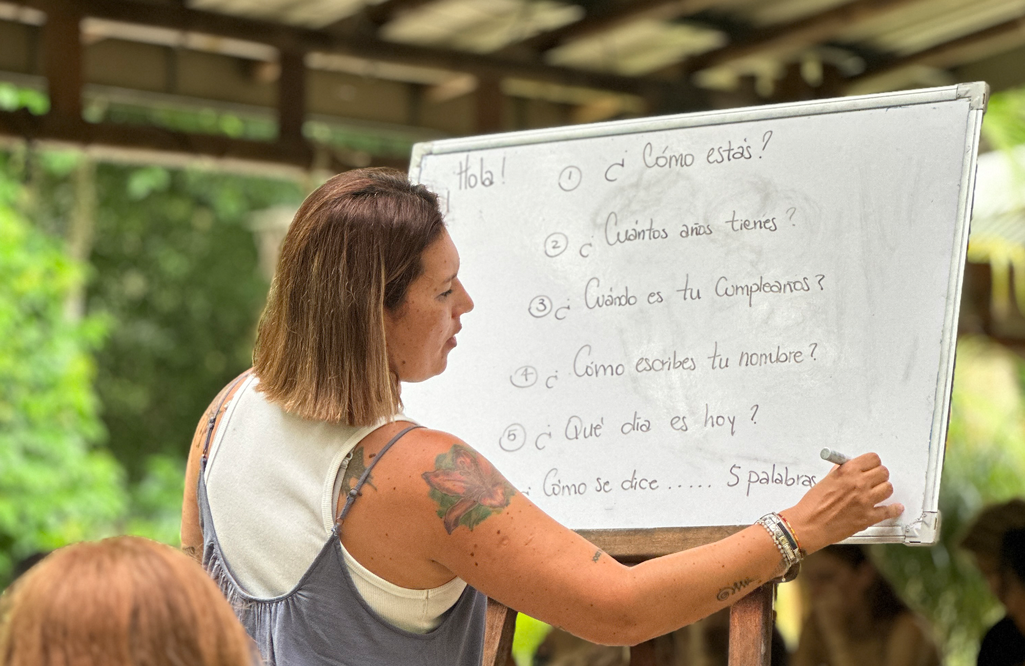 En dame som skriver på et whiteboard og lærer bort spansk. Foto. 