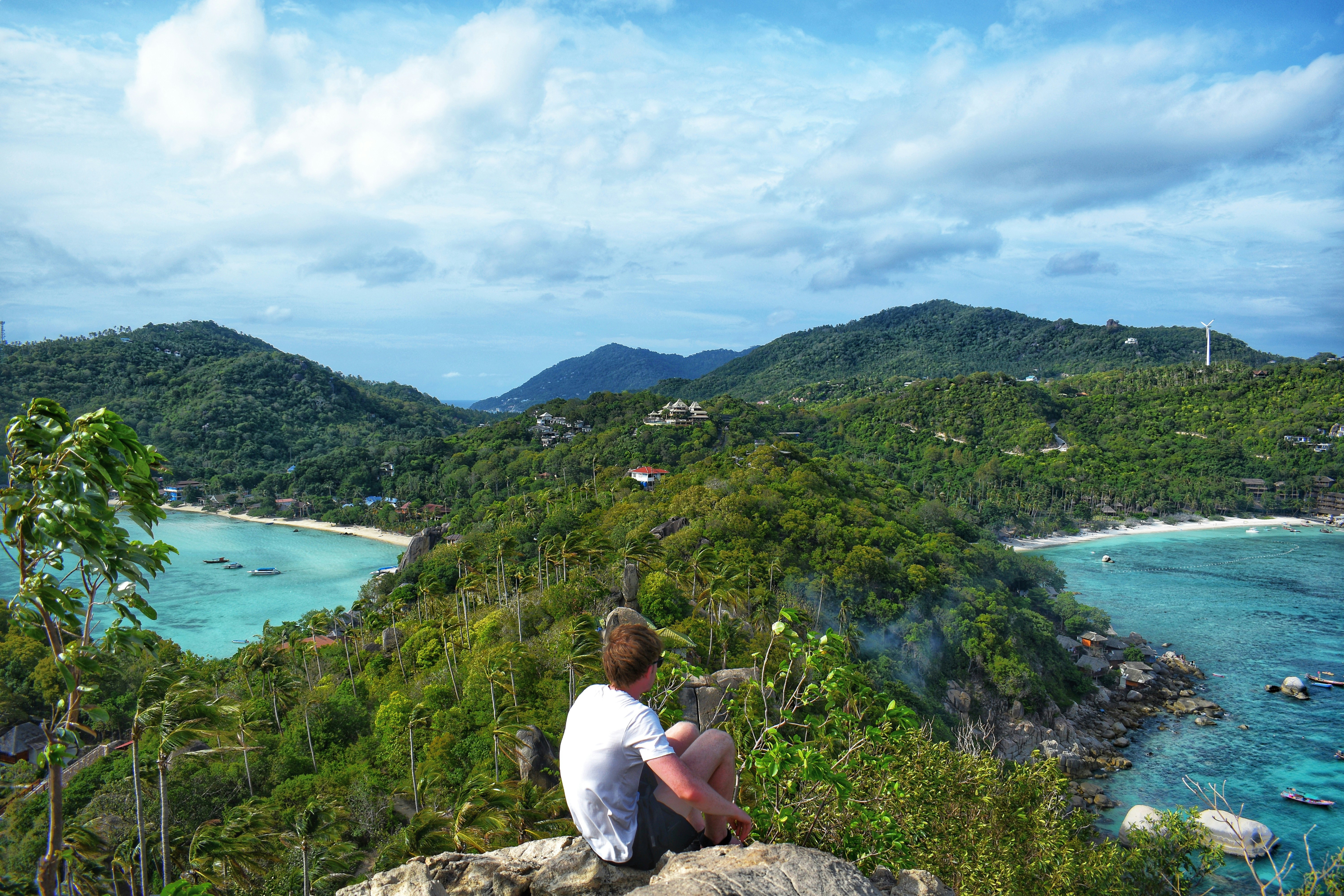 En tenåring som sitter på stener på Koh Tao, Thailand. Foto.