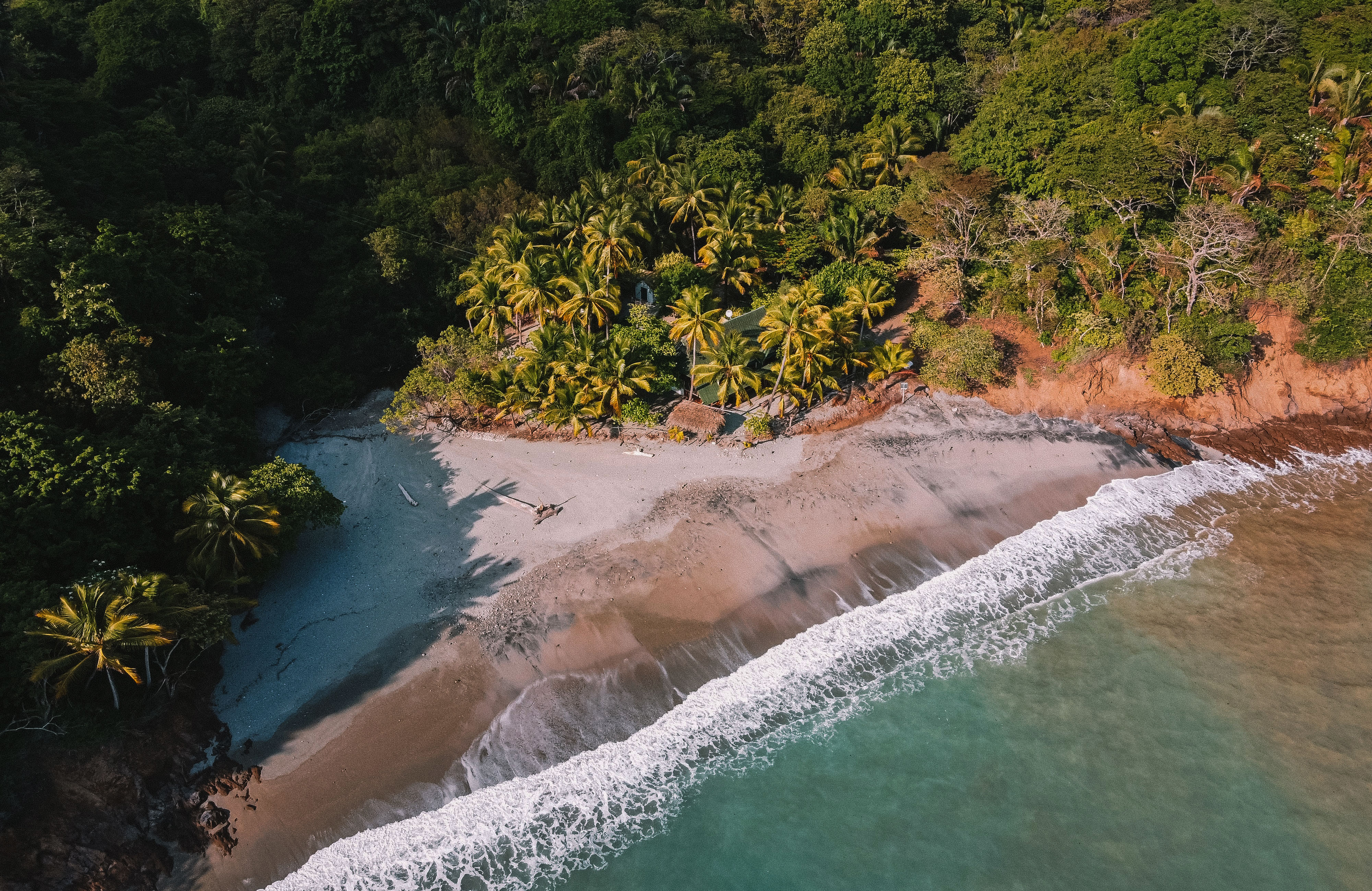 Luftfoto av en bortgjemt sandstrand i Costa Rica, rett ved jungelen